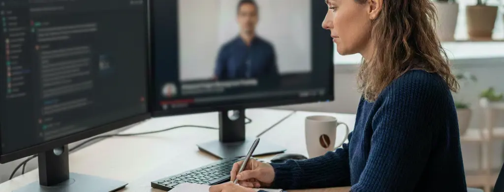 Rapariga em frente a dois monitores, num deles está uma ferramenta de inteligência artificial e no outro um vídeo de uma formação
